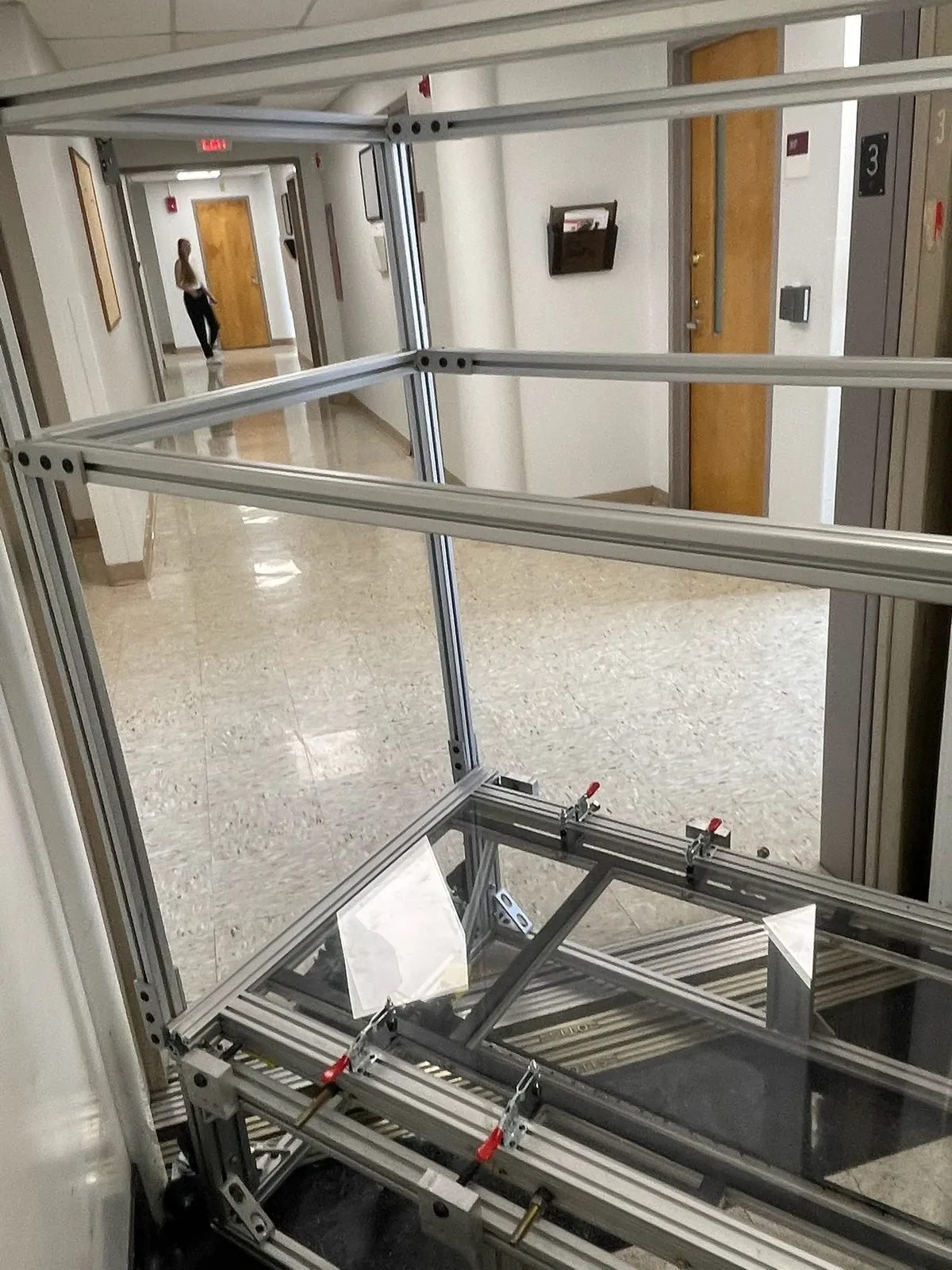 Looking down through the handlebar frame at clear acrylic panels held by red toggle clamps.