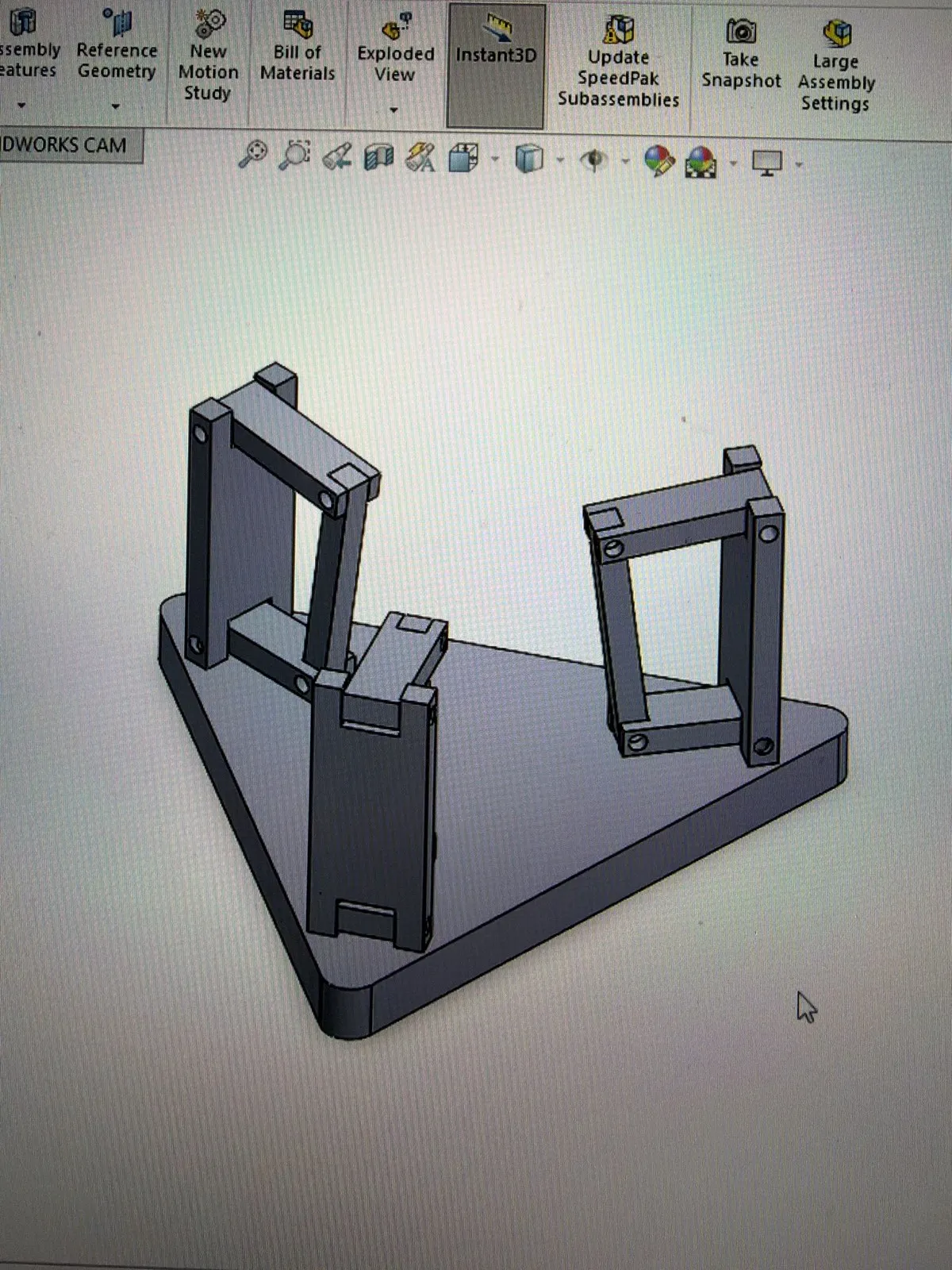 Monitor photo of a SolidWorks model: a triangular base plate with three four-bar linkage towers at its corners.
